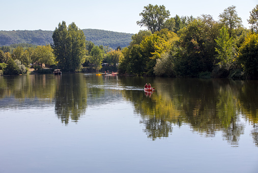 La Roque-Gageac, Dordogne, France - September 4, 2018: Canoeing and tourist boat, in French called gabare, on the river Dordogne at La Roque-Gageac. Aquitaine, France
