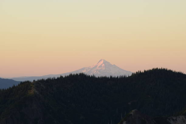 istock Picturesque Glacier Covered Mountain Peak Beyond Silhouetted Mountain Ridge During Vivid Sunrise 1270133695