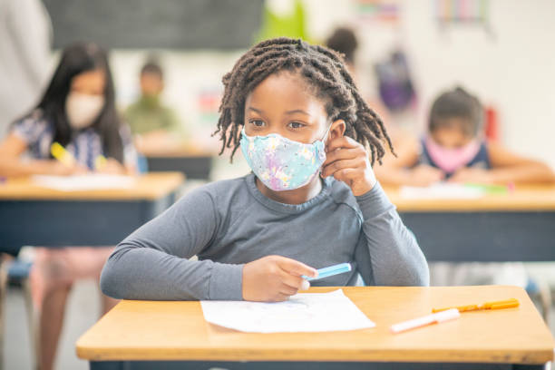 6-jährige, afroamerikanische studentin trägt eine schützende gesichtsmaske im unterricht - 9 year old stock-fotos und bilder
