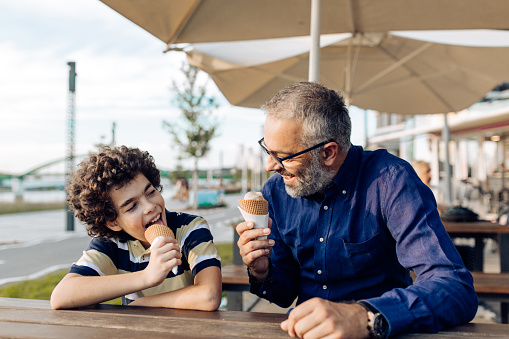 Father and son enjoying together and eating ice cream in the city.