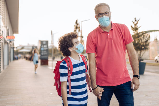 istock Man leading his little boy to school 1270135778