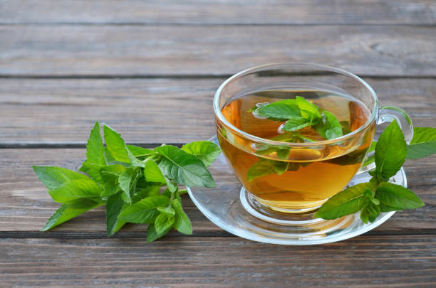 나무 테이블에 신선한 녹색 민트 잎뜨거운 민트 차 한 잔 - mint tea tea peppermint mint 뉴스 사진 이미지