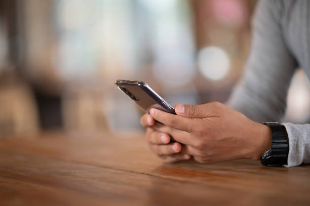 istock Close up of a man using mobile smart phone In cafe bokeh background 1270139795