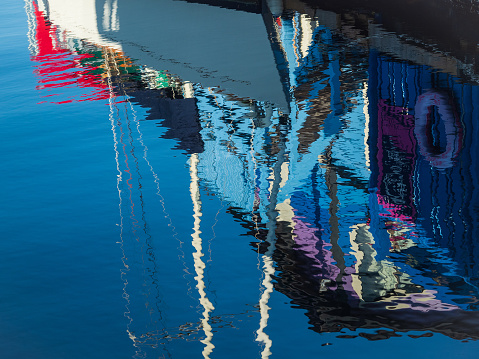 Abstract reflections of sky, trees and building on water with ripples