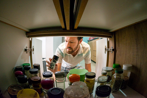 Man selecting spices to prepare a curry at home.