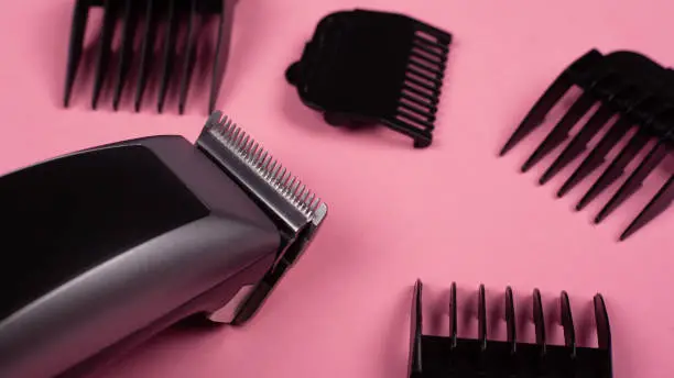 hairdresser's tool. hair clipper close-up on a pink background with nozzles of different sizes.