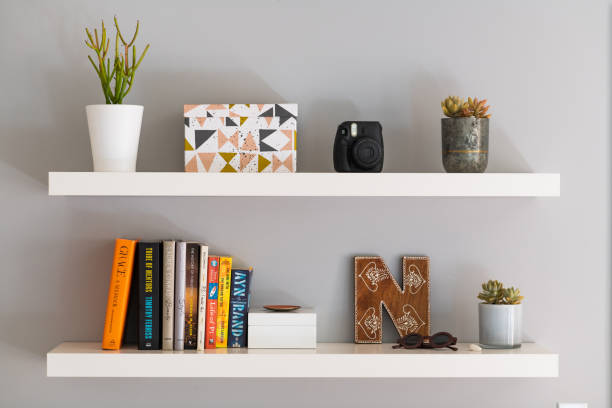 Modern Floating Bookshelves with Books, a Plant and Decorative Box Two white painted modern bookshelves with books,  plants, a decorative storage box and personal items. college dorm photos stock pictures, royalty-free photos & images