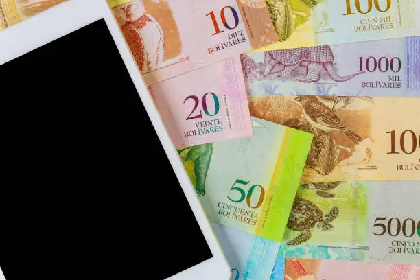 Digital tablet computer with Venezuelan Bolivar banknote with Venezuela economic of different currency paper bills