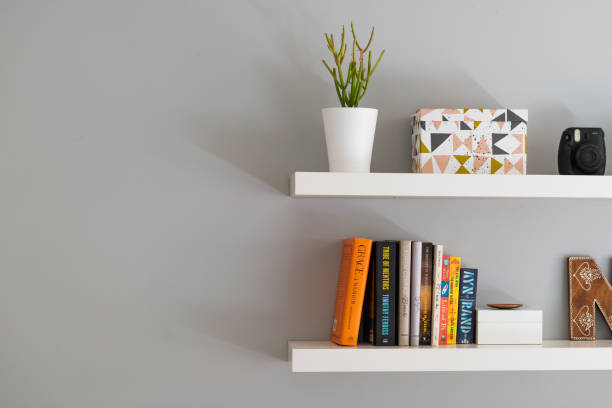 modern floating bookshelves with books, a plant and decorative box - levitation imagens e fotografias de stock