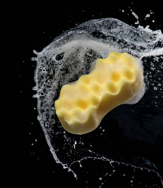 istock Water containing soap splashing with yellow sponge isolated on black background 1270157958