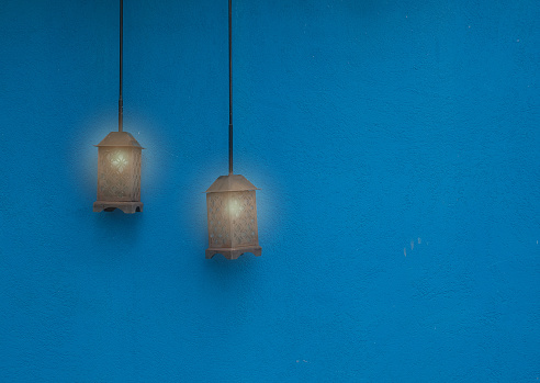 Vintage lamp hanging from the ceiling with blue wall.