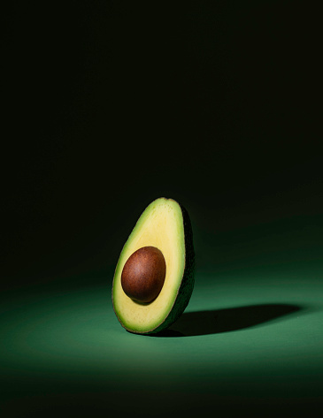 A studio shot of an avocado cut in half with dramatic lighting.