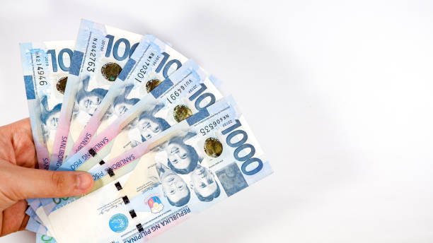 Paying of multiple Philippine Peso 1000 bills on white background Philippine currency bill background with hand philippines currency stock pictures, royalty-free photos & images