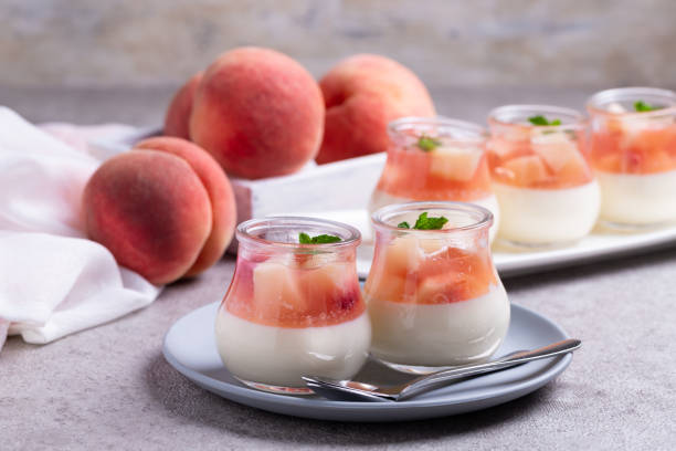 kuvapankkikuvat ja rojaltivapaat kuvat aiheesta kotitekoinen panna cotta, jossa on persikka- ja persikkahyytelöviipaleita lasipurkeissa harmaalla betonitaustalla. - mousse dessert