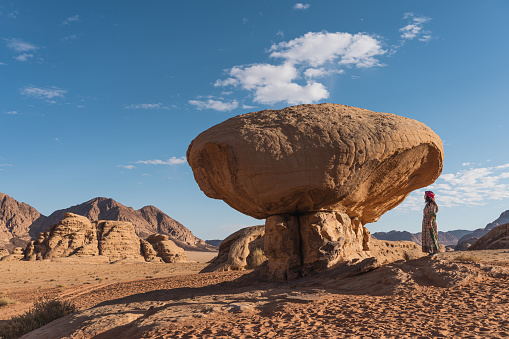 Young Asian woman standing near mushroom stone, landmark of Wadi Rum red desert in Jordan, Arab, Asia