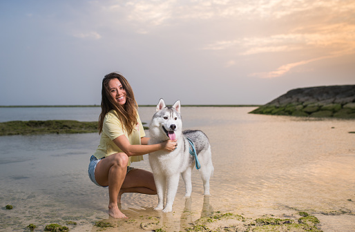 A half American half Japanese woman with her Siberian Husky enjoying time at the beach at sunset.