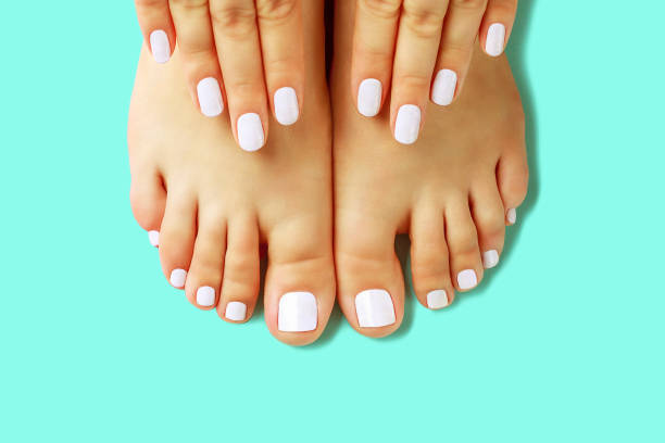 istock Female hands with white manicure and pedicure on blue background, top view 1270186243