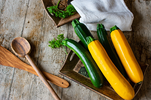 fresh and uncooked zucchini with green and yellow color placed on a wooden rustic table
