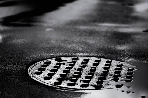 A dark image of a manhole cover in an asphalt street.
