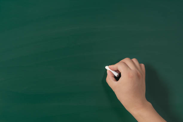istock A mature hand writing or drawing on a clean green blackboard with a white chalk 1270192318