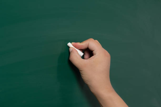 istock A mature hand writing or drawing on a clean green blackboard with a white chalk 1270192329