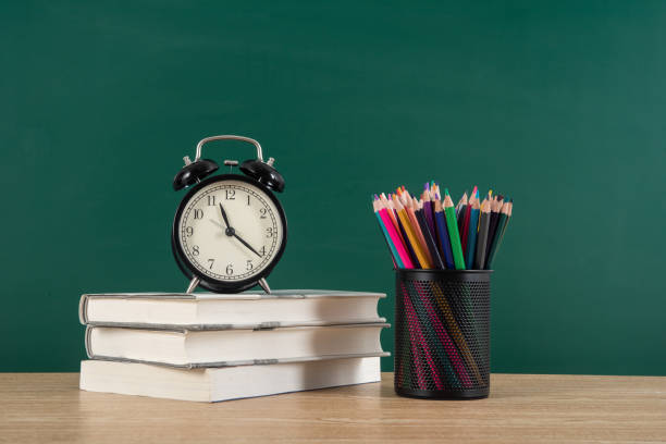 istock Alarm clock on stack of textbook with chalkboard or blackboard background copy space 1270192374