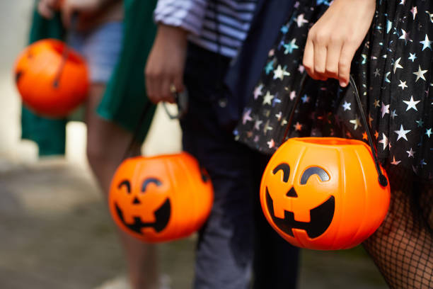 Treats for Halloween Close-up of children with pumpkins bags playing trick or treat outdoors trick or treat photos stock pictures, royalty-free photos & images
