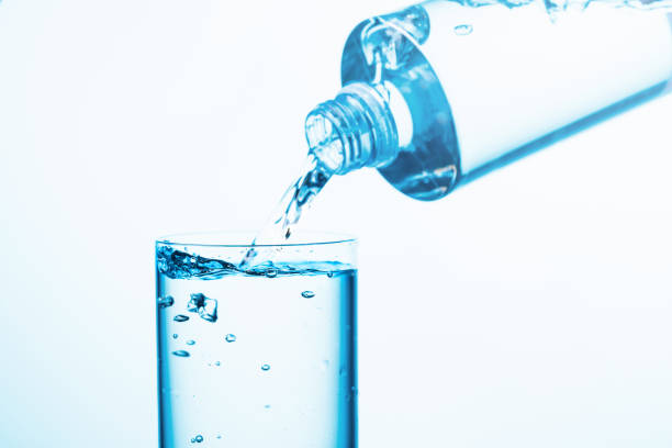 istock Pouring water from a bottle into glass on a blue background. 1270202622