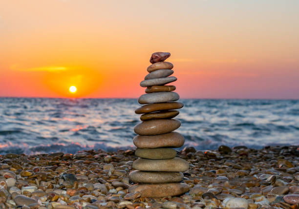 istock Pyramid of stones on pebble beach at sunset 1270205097