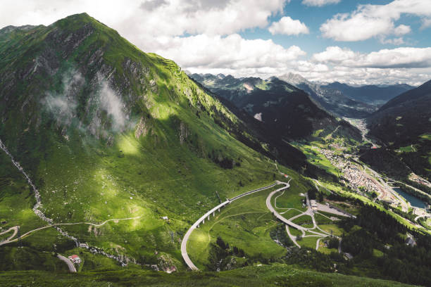 Clouds gathering over the mountains above St. Gotthard pass in Switzerland Alps. Road up the mountain with no cars.