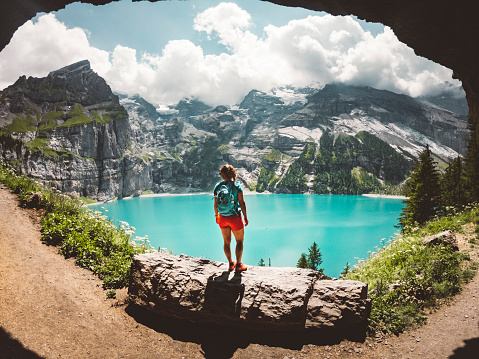 Woman hiking in the mountains by the Oeschinen lake in Berner Oberland region in central Switzerland.  Hiker hiking in Swiss alps in the summer.