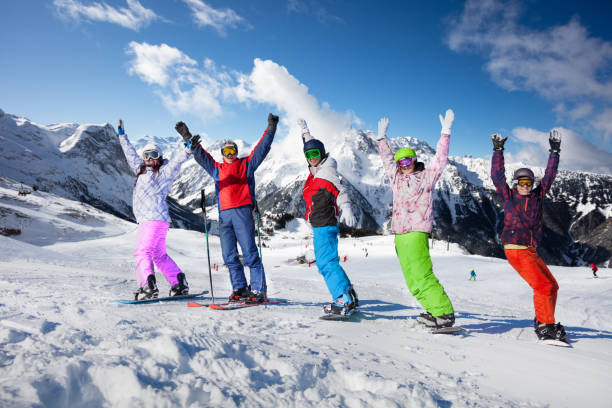 istock Many adults stand on ski and snowboards lift hands 1270206440