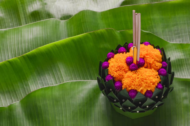 Banana leaf Krathong for Thailand full moon or Loy Krathong festival. Banana leaf Krathong that have 3 incense sticks and candle decorates with flowers for Thailand full moon or Loy Krathong festival puts on green banana leaves. krathong stock pictures, royalty-free photos & images