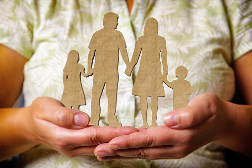 Wooden figures - family, children and parents in a line holding hands and standing in the hands of a woman