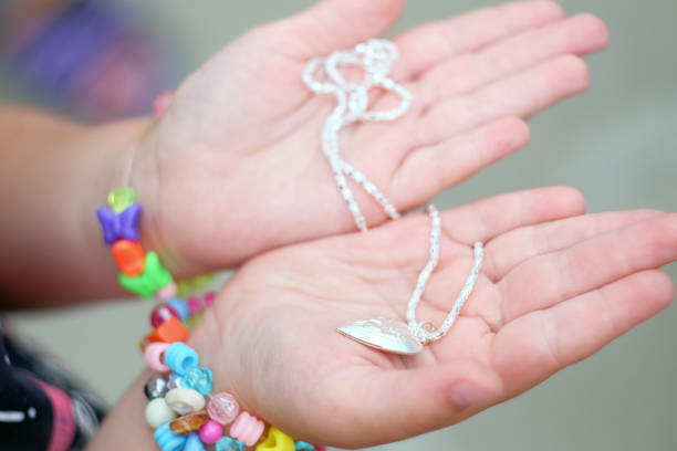 Children's hands holding a beautiful chain with a pendant so close stock photo