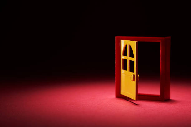 miniature toy door frame and door open on black background time machine concept