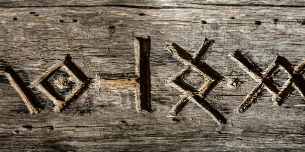 Photo of Ancient runes and hieroglyphs carved on a dry wooden board