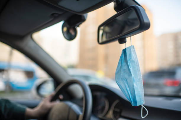 istock Protective face mask hanging on the rearview mirror in a car 1270223639