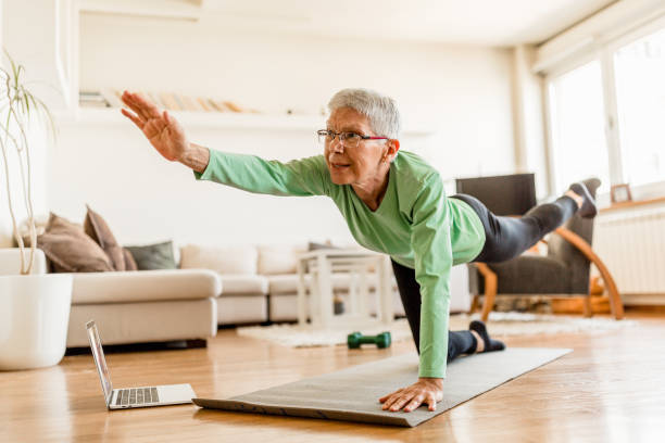 istock Active senior woman home exercising with online coach 1270225705