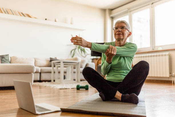 istock Active senior woman home exercising with online coach 1270225744
