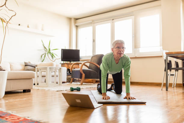 istock Active senior woman home exercising with online coach 1270225749