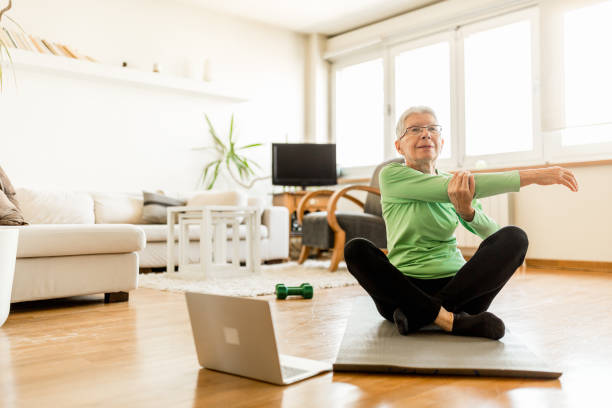 mulher idosa ativa em casa se exercitando com coach online - healthy lifestyle yoga vitality flexibility - fotografias e filmes do acervo