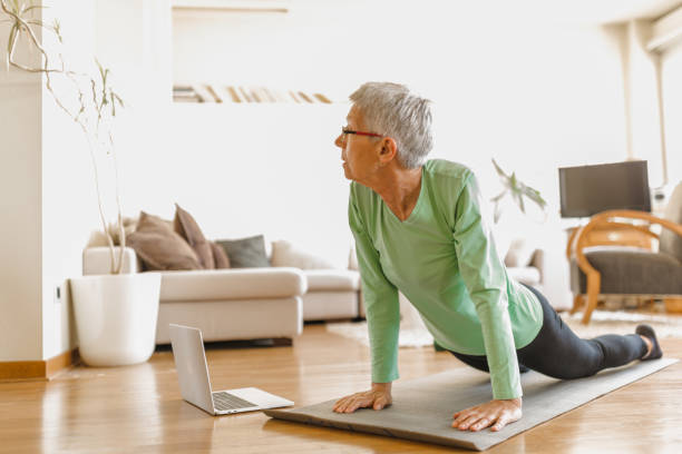 istock Active senior woman home exercising with online coach 1270225751