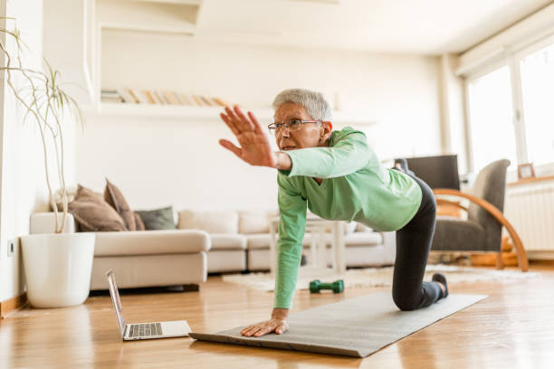 istock Active senior woman home exercising with online coach 1270225760