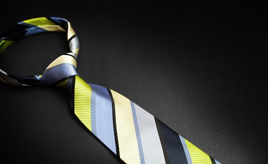 Men's striped tie in different colors isolated on black background.
