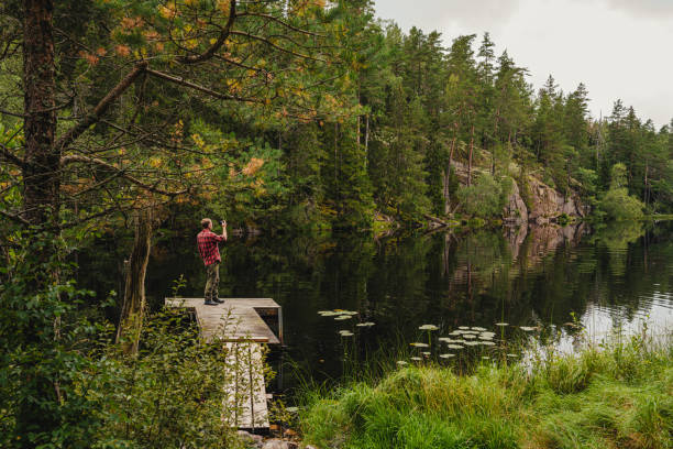 istock Man on a jetty in a lake by the forest nature landscape 1270228921