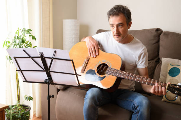 istock Man looking at score learning to play guitar at home 1270229918