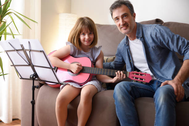 professeur de guitare enseignant une fille dans son salon - privacy partition photos et images de collection