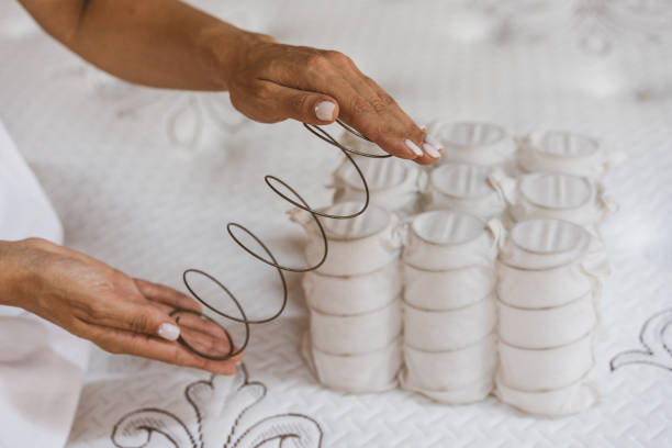 Mattress spring in the hands of a woman. Pocket independent spring. The concept of filling a mattress. Mattress spring in the hands of a woman. Pocket independent spring. The concept of filling a mattress. Technology Concept broken spring stock pictures, royalty-free photos & images