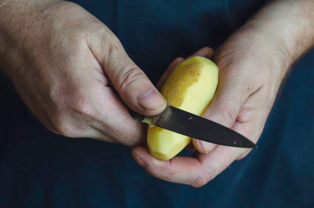 istock A mature man peels raw potatoes with a kitchen knife. 1270230406